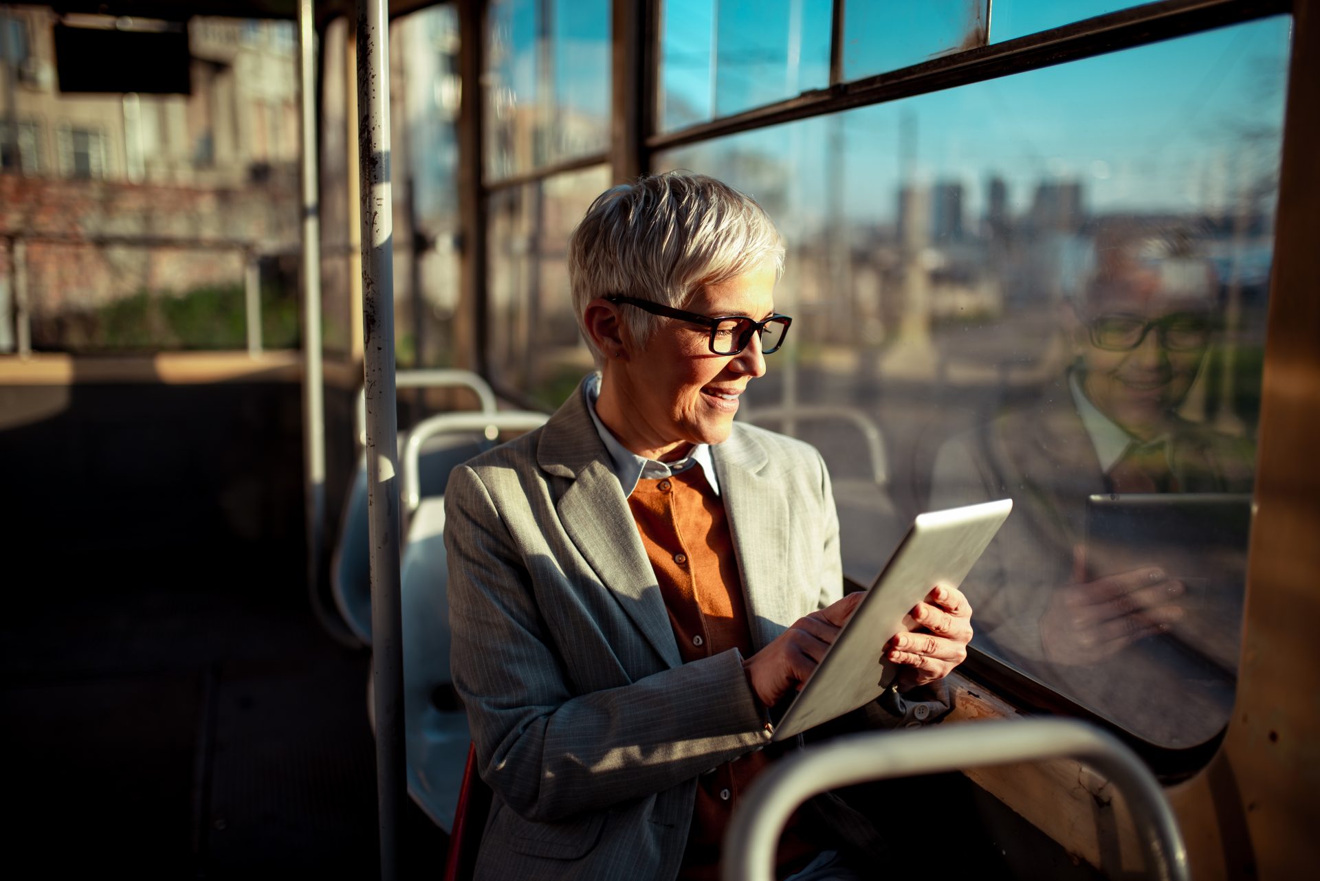 Smiling woman using a tablet on the bus.