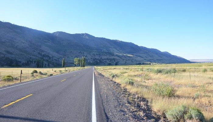 A rural road leads up to a mountain.