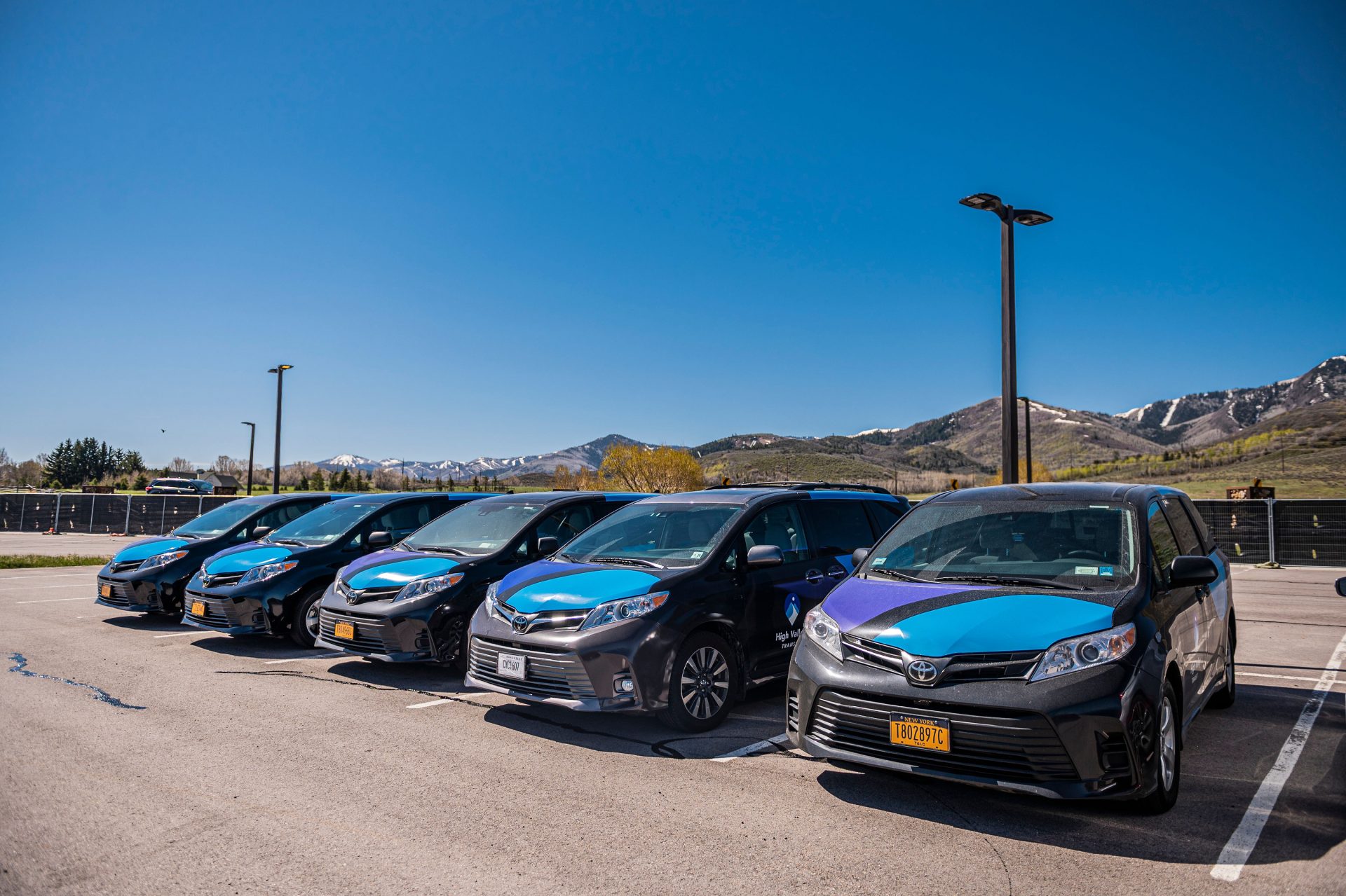 Five Micro vehicles parked in a parking lot on a sunny day, mountains are in the background